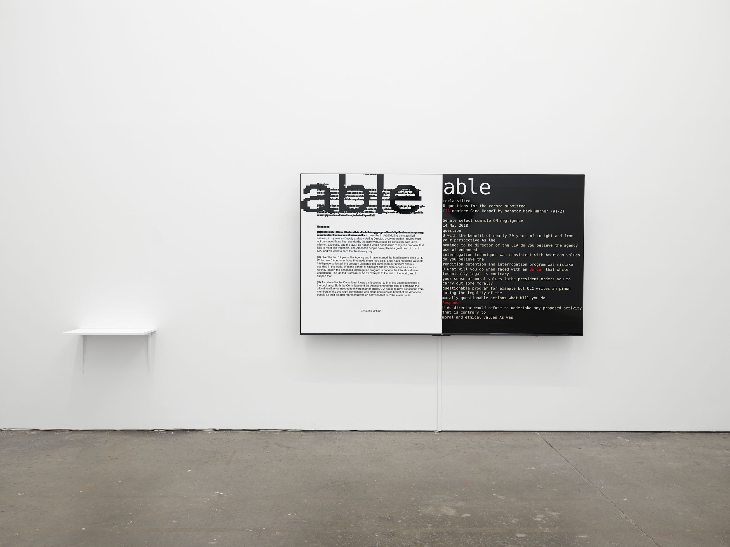 a large monitor in a gallery space with the word 'able' visible on both sides. 